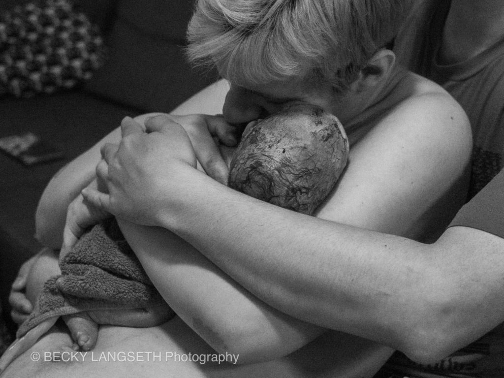 A mother embraces her new baby for the first time at a home birth in Seattle. This images shows why you should hire a birth photographer and how important it is to capture the embrace in an image.