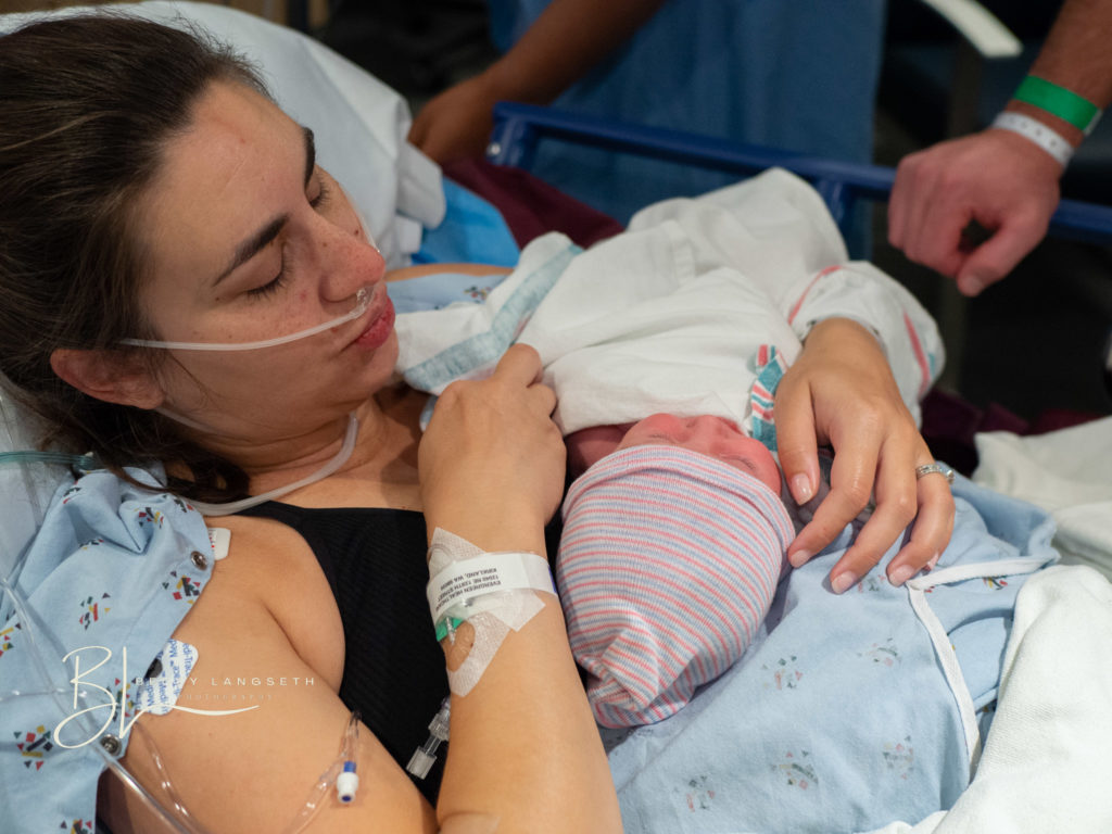 mother holding her baby after a c-section birth and looking down at her new baby.