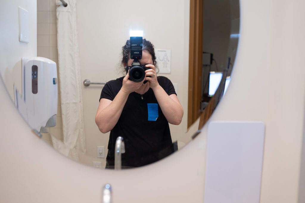 Seattle Birth Photographer, Becky Langseth is taking a photo of herself using the bathroom mirror in one of the labor and delivery rooms at St. Michael Medical Center's Family Birth Center in Silverdale, Washington after she finished photographing a birth. 