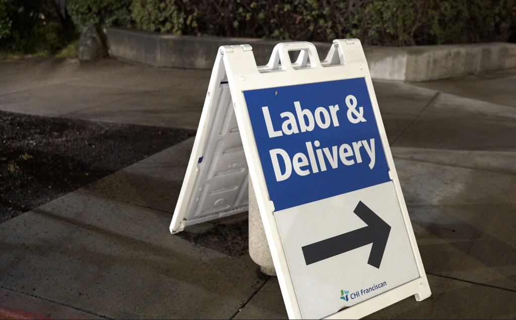 A signicade in front of birth center in Seattle that says, "Labor & Delivery" with an arrow pointing in the direction of the birth center in Seattle.