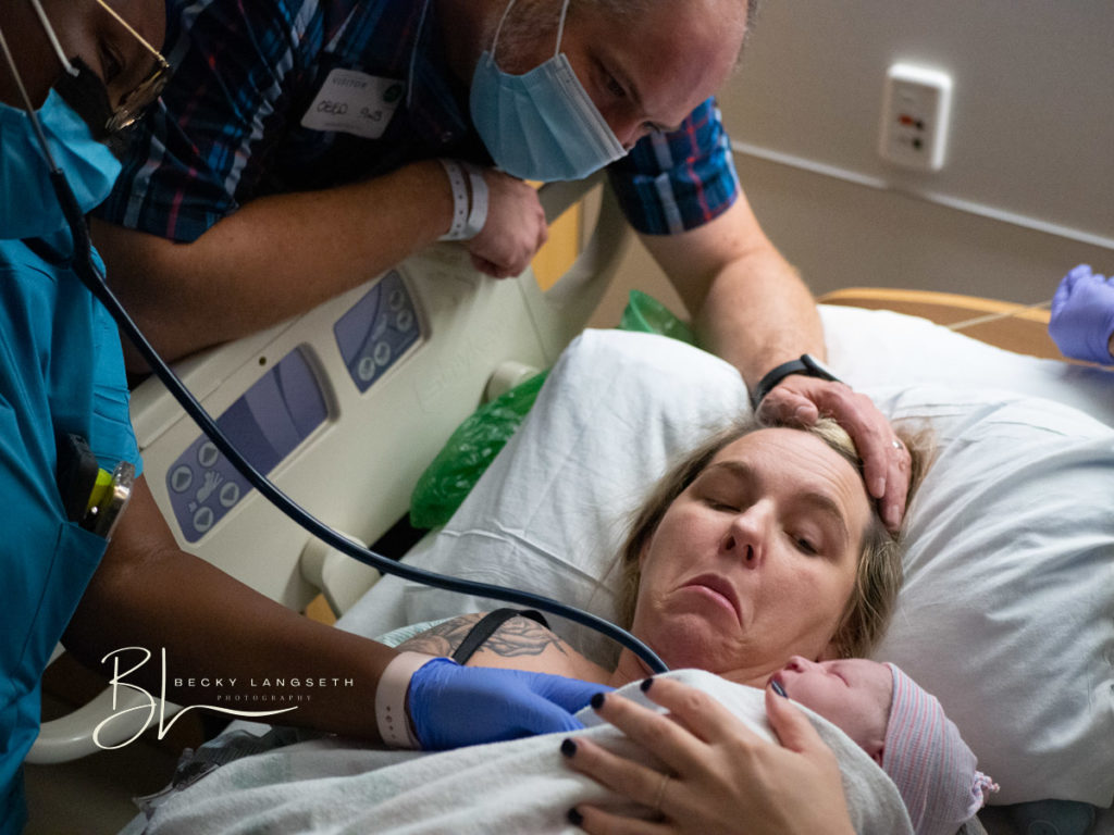 A mother is holding her newborn for the first time in a hospital bed after giving birth at Overlake Medical Center in Bellevue, WA captured by Seattle Birth Photographer, Becky Langseth. This photo is proof of an example of  parents interviewing their birth photographer before giving birth to ensure that their birth photographer would be a good fit for them and their family.