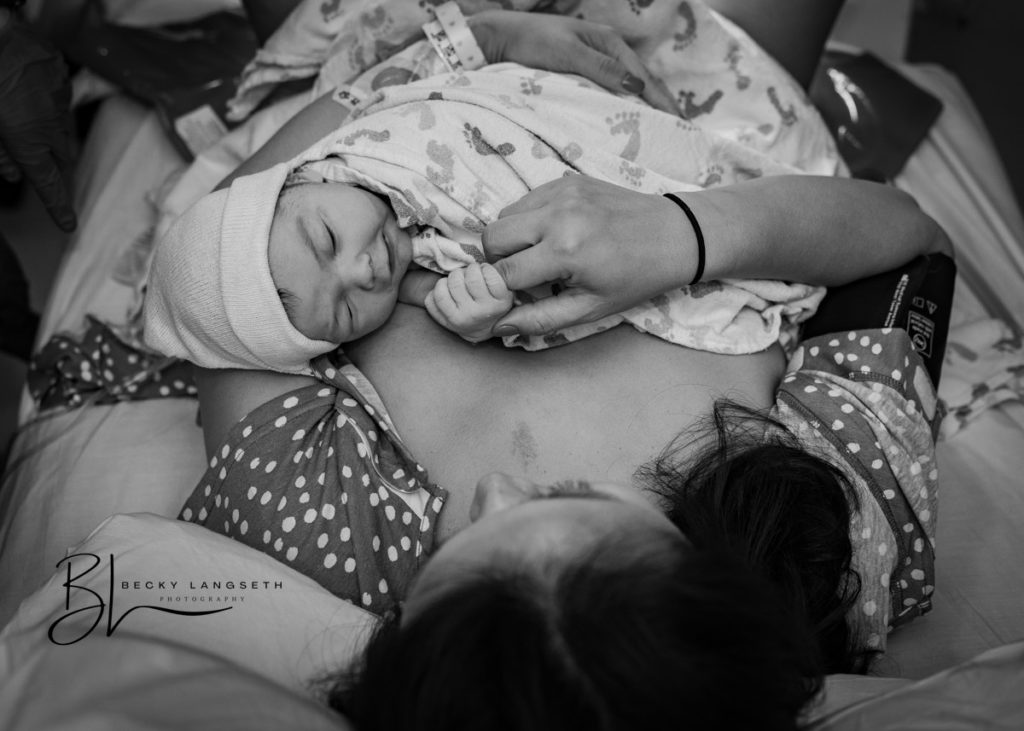 A mother is holding her baby's tiny hand and snuggling for the first time after giving birth at the Birth Center at UW Medical Center - Montlake in Seattle, WA.