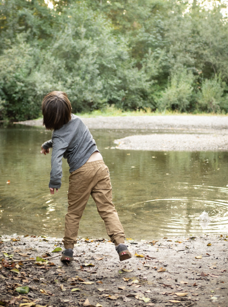 A boy throws a rock into the pond at Wallace Swamp Creek Park in Kenmore, WA.