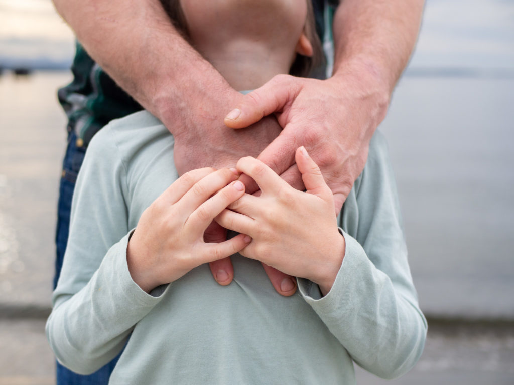 A close up image of a father's hands embracing his son in Edmonds, WA.