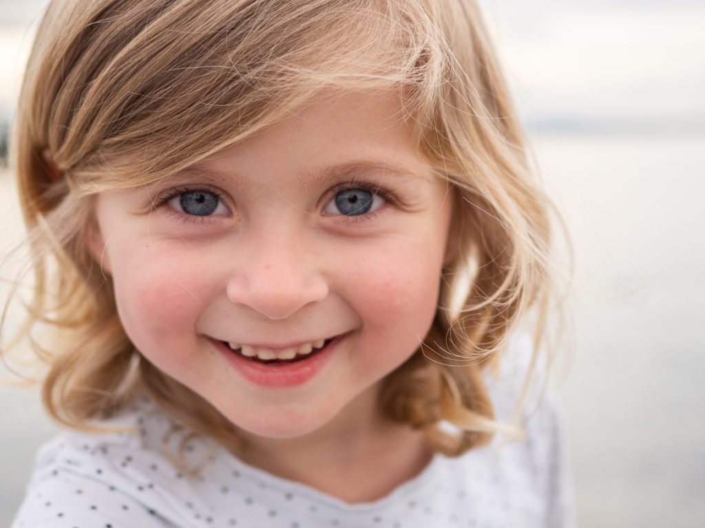 A little girl smiles at Edmonds Beach, captured by Edmonds Family Photographer, Becky Langseth.