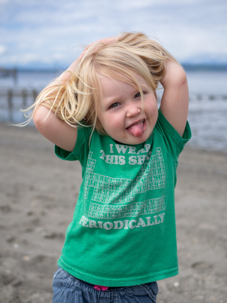 a little girls is sticking her tongue out at the camera on Edmonds beach.