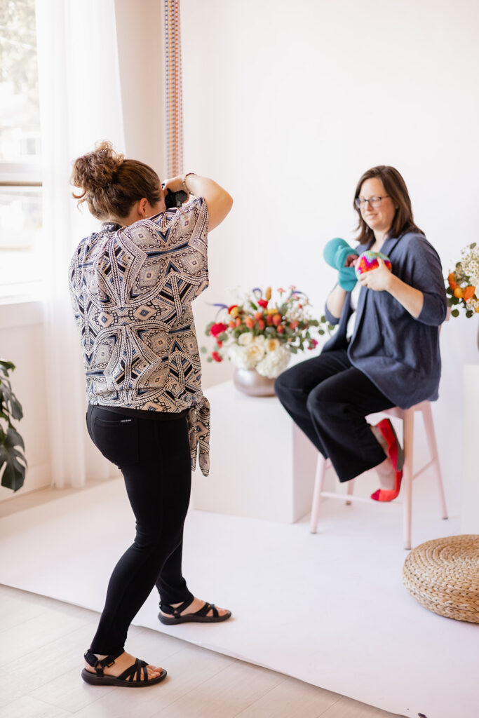 Becky Langseth, Seattle Birth Photographer, takes a portrait of Rachael Katz, Postpartum Doula & CLE, in the North City Studio, in Shoreline, WA as she demonstrates how to get a proper latch at the 2023 Seattle Mother's Day Maternity Market.