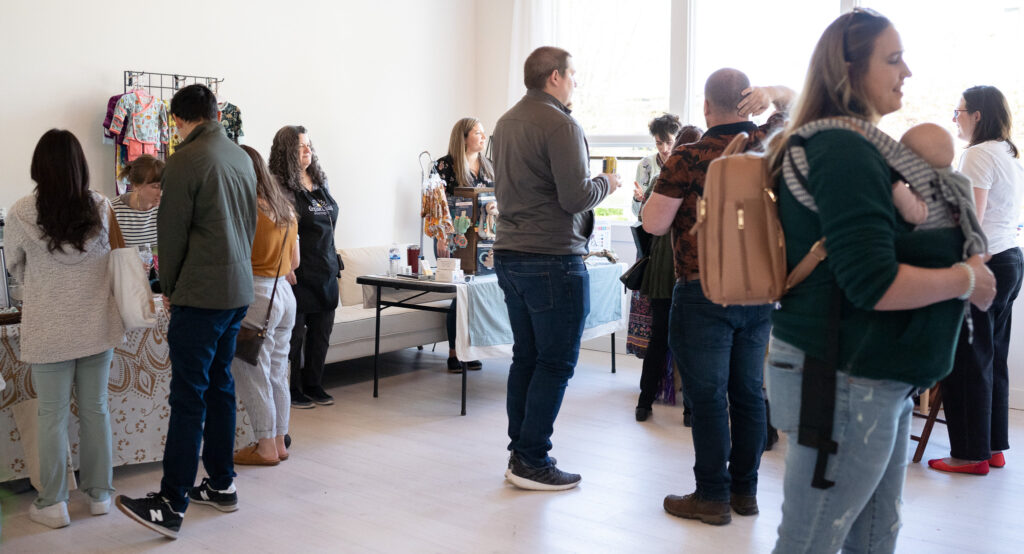 a wide angle view of the 2023 Seattle Mother's Day Maternity Market with people moving around from table to table looking at all the resources the perinatal vendors have to offer.