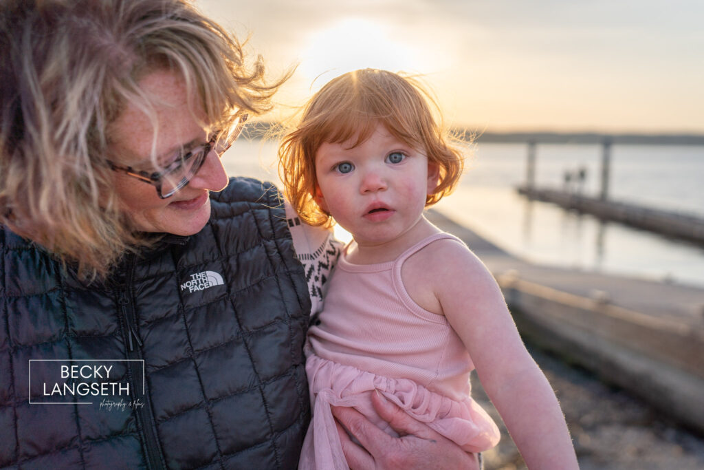 A close up image of a grandmother holding her granddaughter at the beach at sunset in Mukilteo, WA.