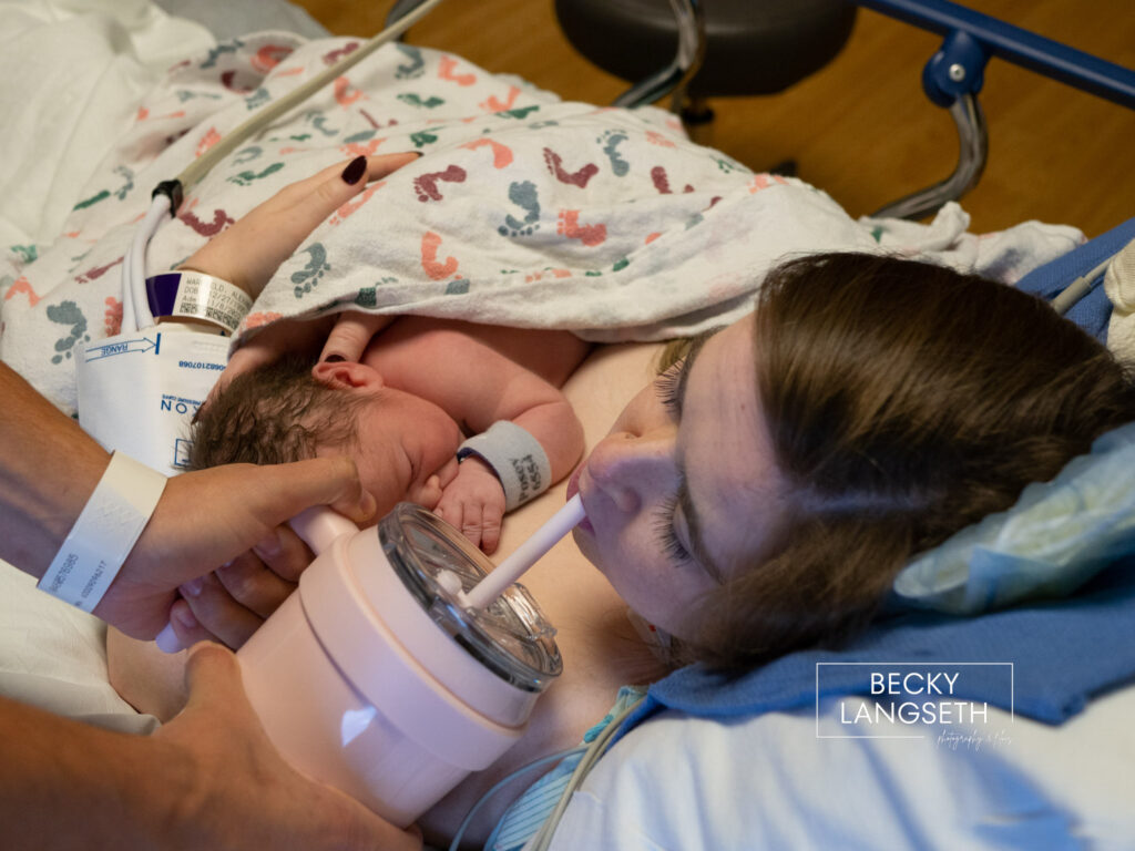 A new mother takes a drink of water while holding her baby during the golden hour at Swedish Issaquah Hosptial in Issaquah, WA.