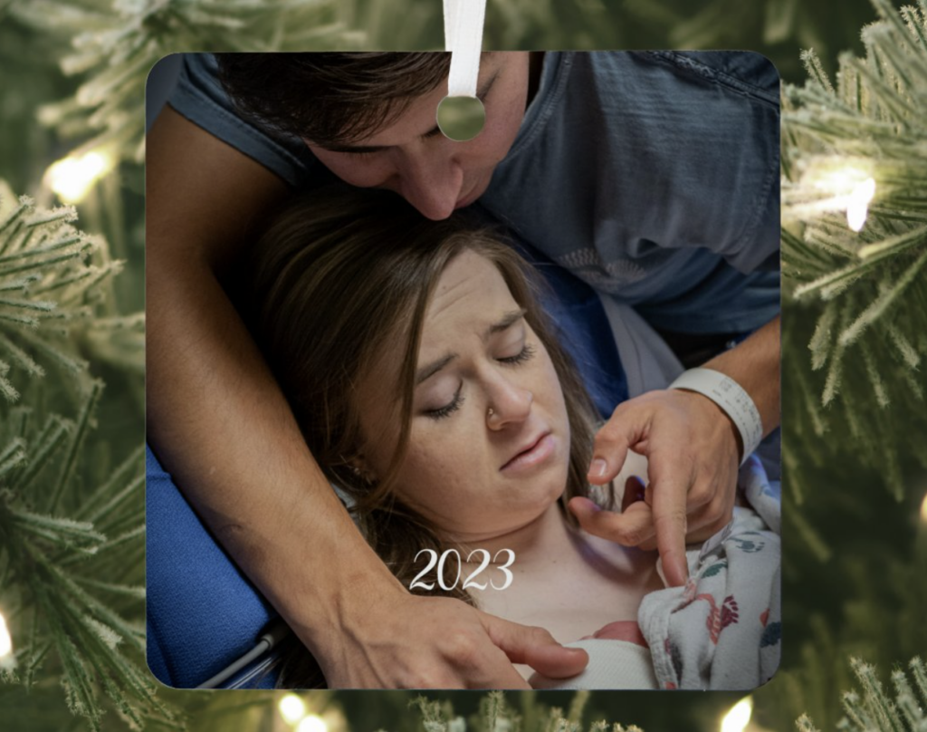 A Christmas ornaments with a birth photo on it is hanging in a Christmas tree. (An example of what to do with your birth photos.)