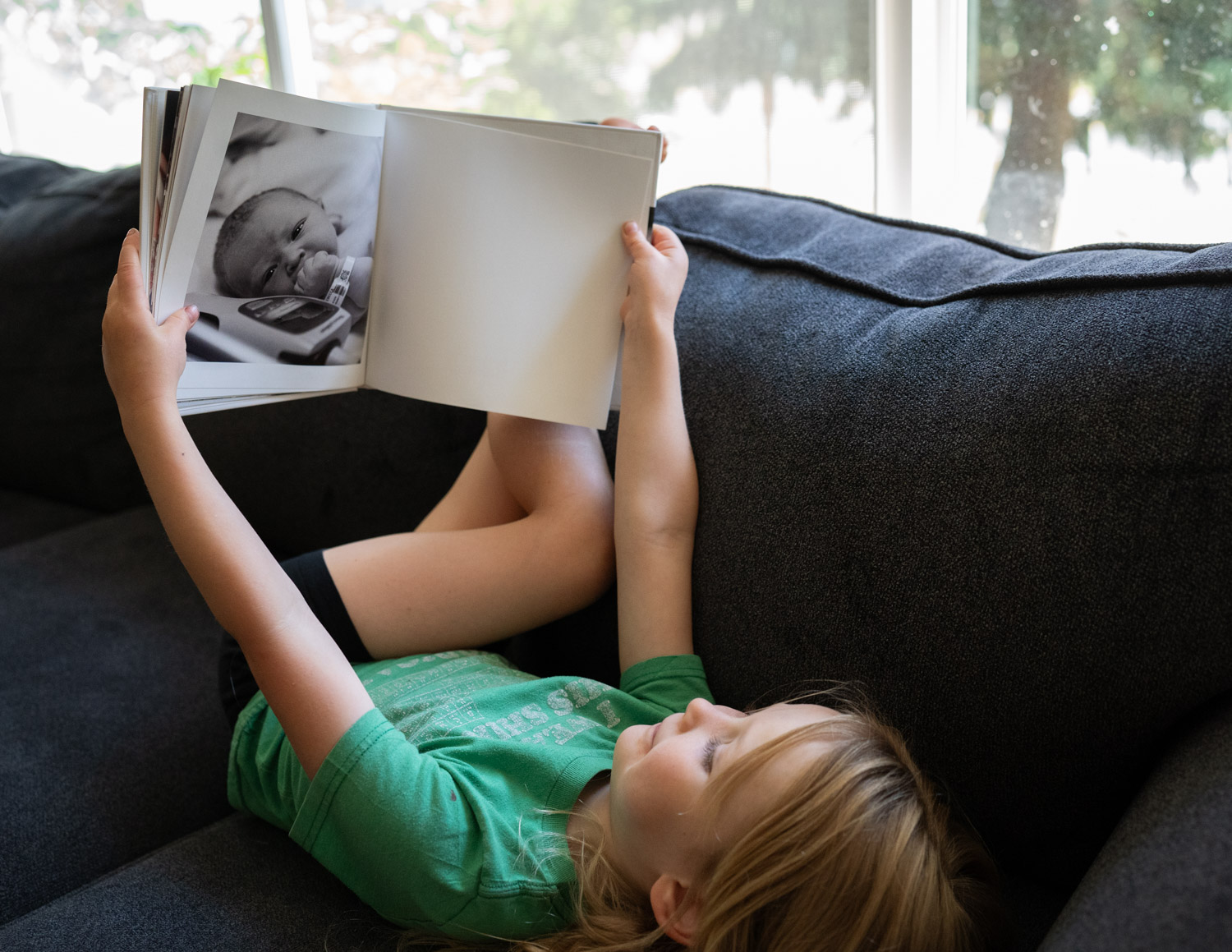 A small child is looking at a photo album of the day she was born.