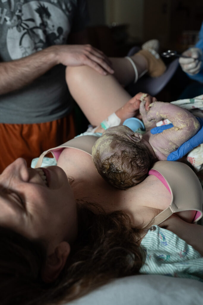 Answering common questions about birth photography by showing this photo as an example of how birth photography can be discrete. This image contains a mother holding a baby for the first time.