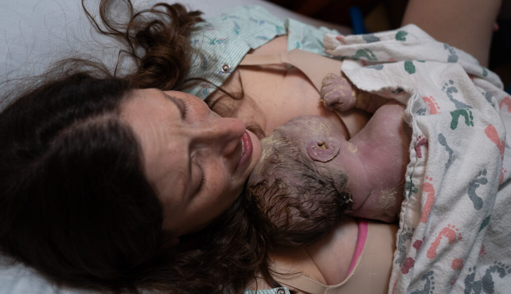 Answering common questions about birth photography by showing what birth photography is in this photo of a mother holding her baby for the first time after giving birth.