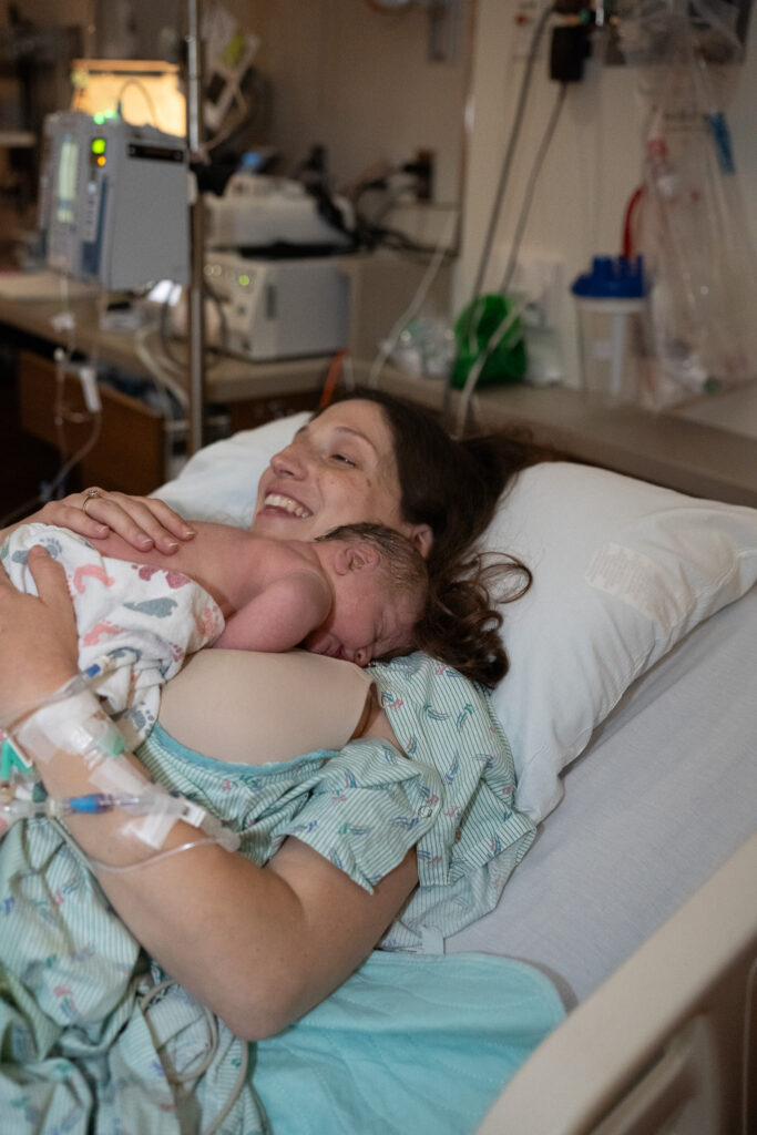 Mother holds her newborn baby with joy in a hospital bed