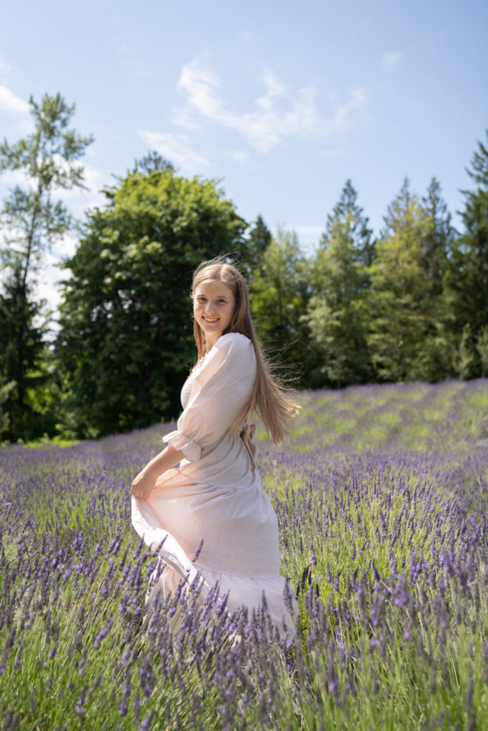 a girl in a cream dress twirling in a purple lavender field