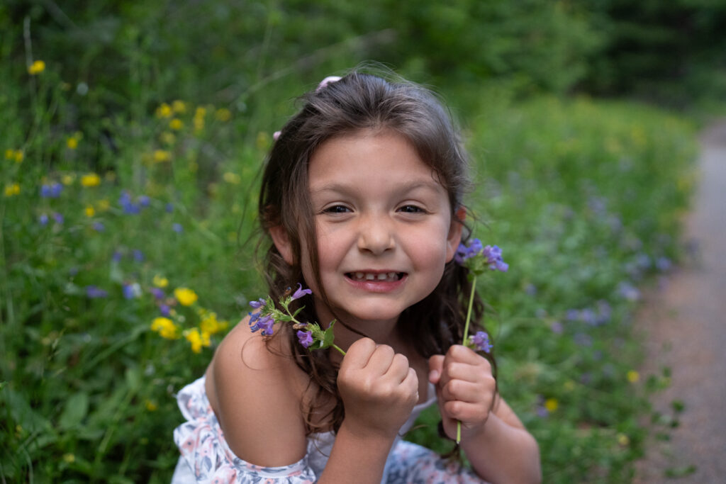 a little girl holds wildflowers in Washington state.