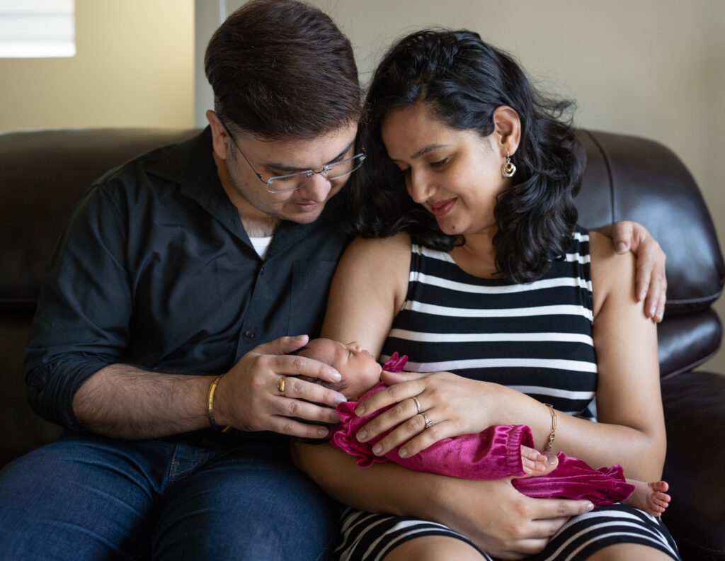 Mom and dad hold their 2 week old baby at their home in Bothell, WA during a newborn photo session.