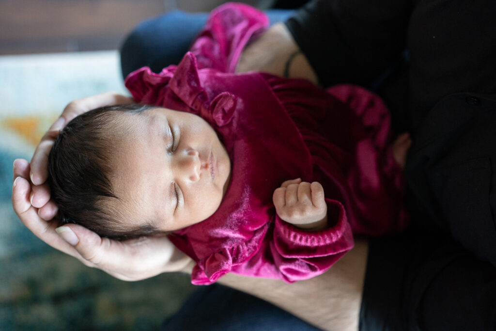 A close up images of a tiny baby in her father's hands at her new home in Bothell, WA.