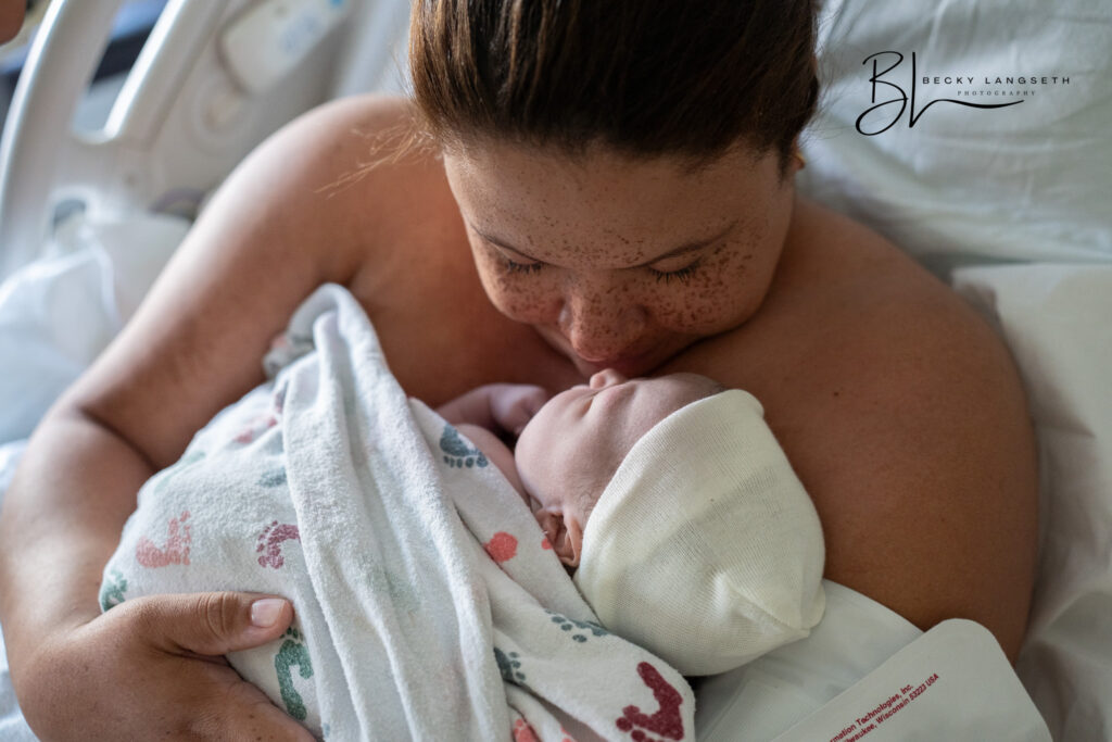 A mother is kissing and smelling her new baby after giving birth in a hospital bed at Swedish First Hill in Seattle.