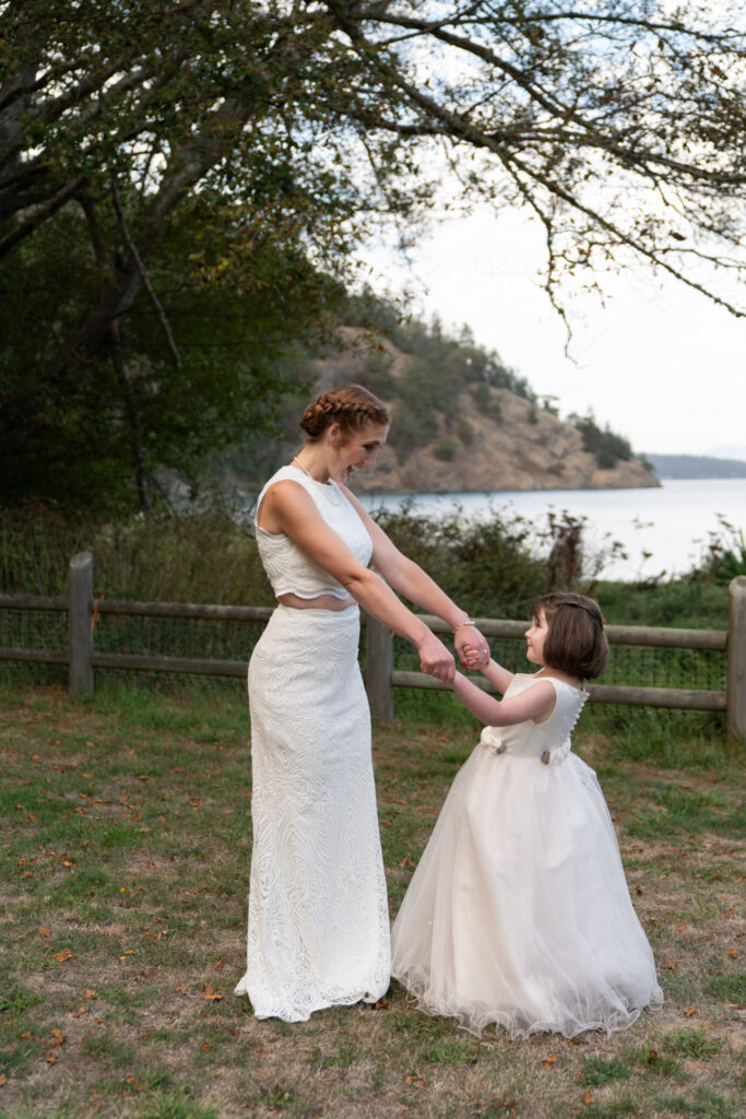 bride dances with her daughter just before her wedding with Cornet Bay in the background