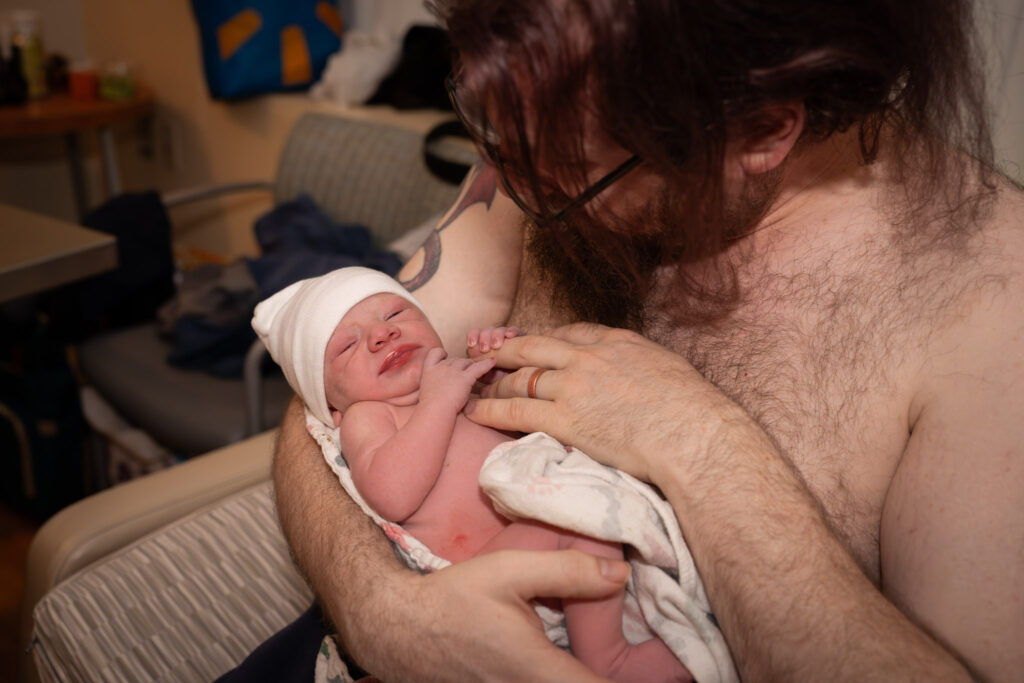A new dad holding his brand new son skin-to-skin in a hospital room