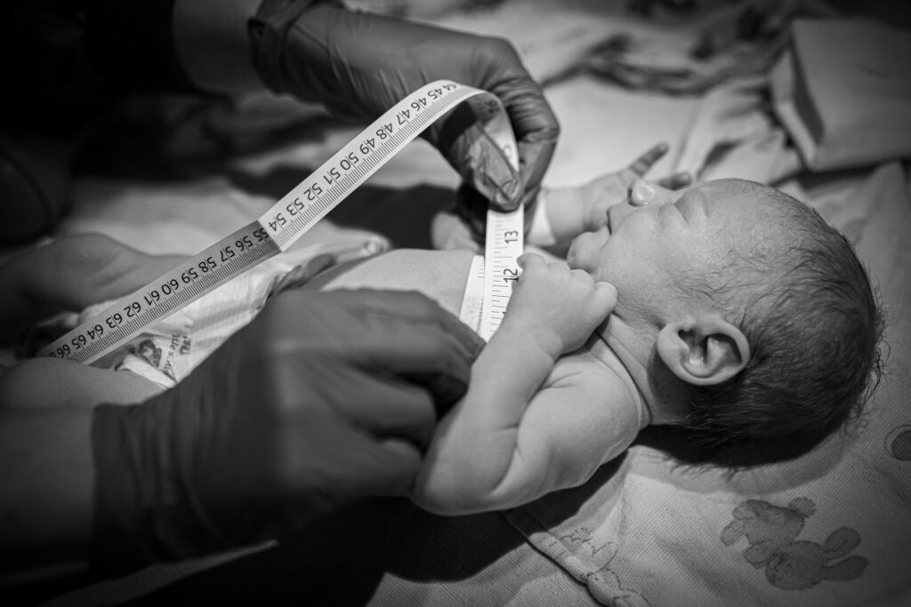 a baby being measured by a measuring tape in the newborn baby warmer at a hospital