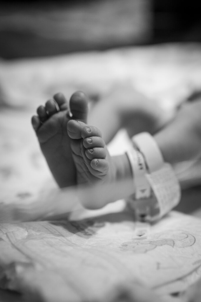 tiny close up of baby feet with hospital bands around the ankles