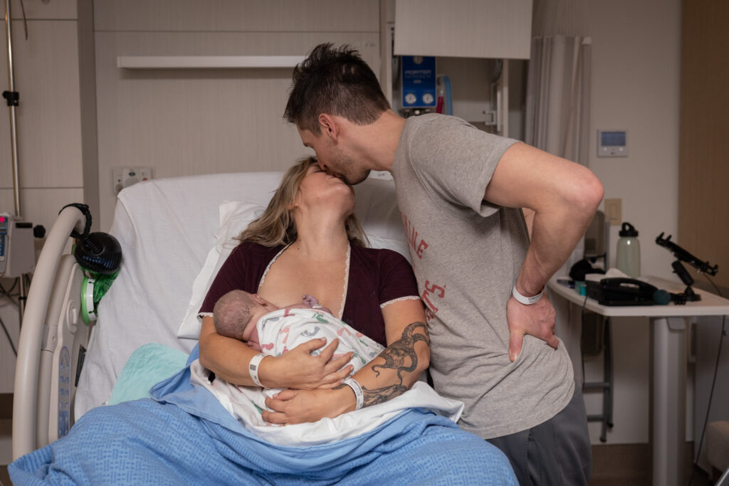 New mom and dad kiss while mom holds the baby at UW Northwest Childbirth Center