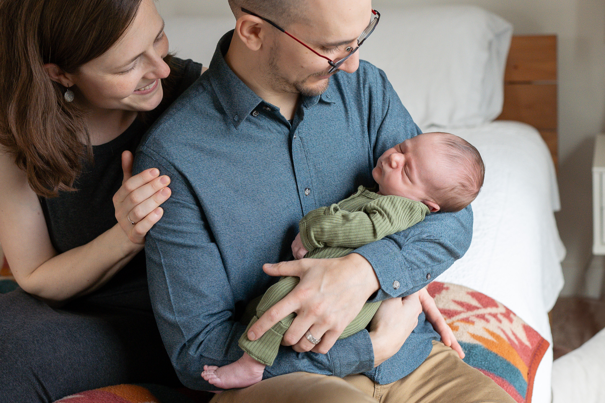 a mother and father hold hold their new baby in their bedroom.