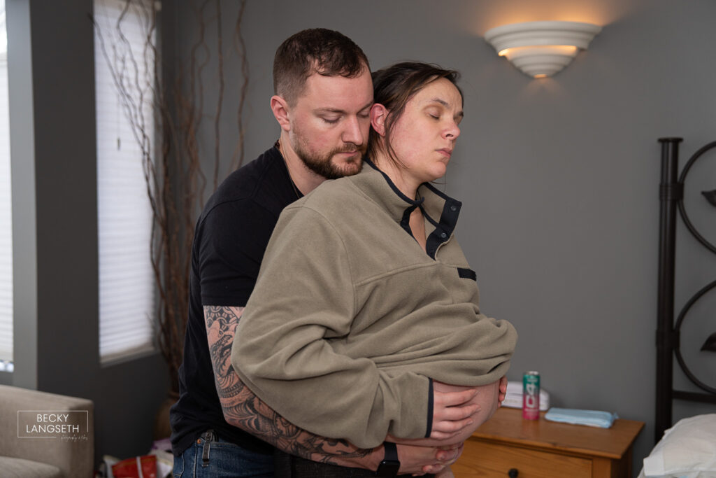 a husband holds his pregnant wife as she goes through a contraction