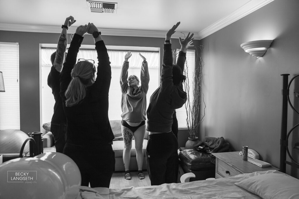 everyone is staying up with their hands in the air  to help a laboring mother relax at a birth center as she labors in Seattle