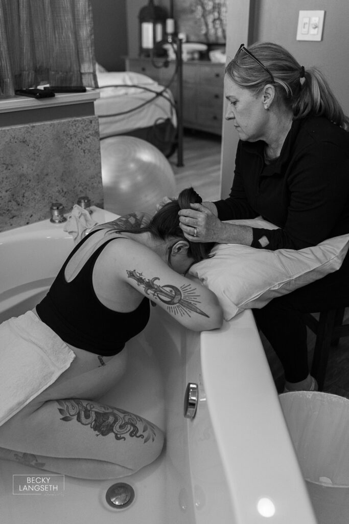 a doula rubs the head of a laboring mother while she goes through a contraction