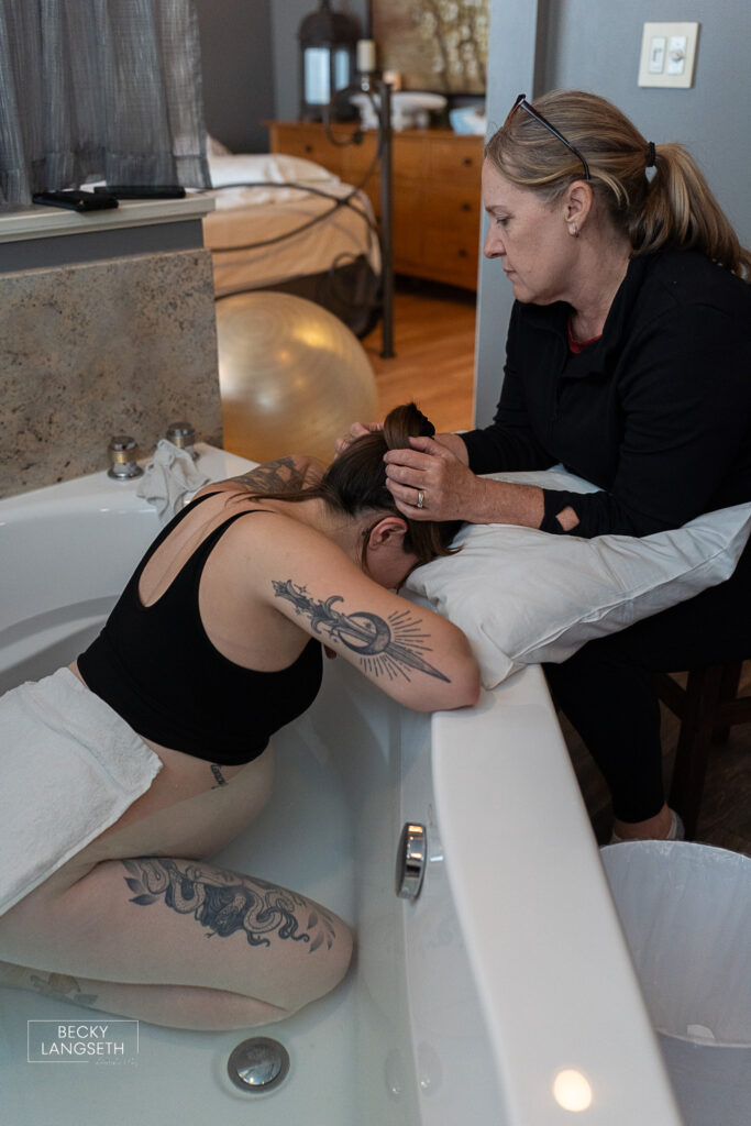 a doula supports a laboring woman in a birth pool