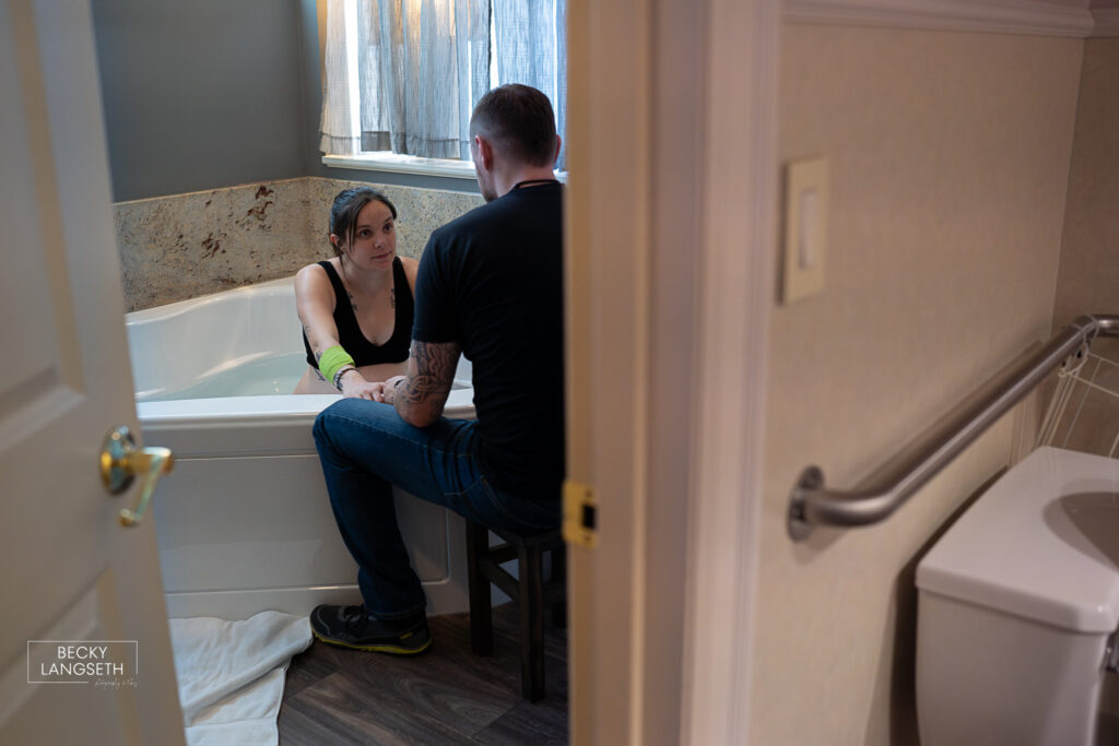 a husband is supporting his pregnant wife in the labor tub