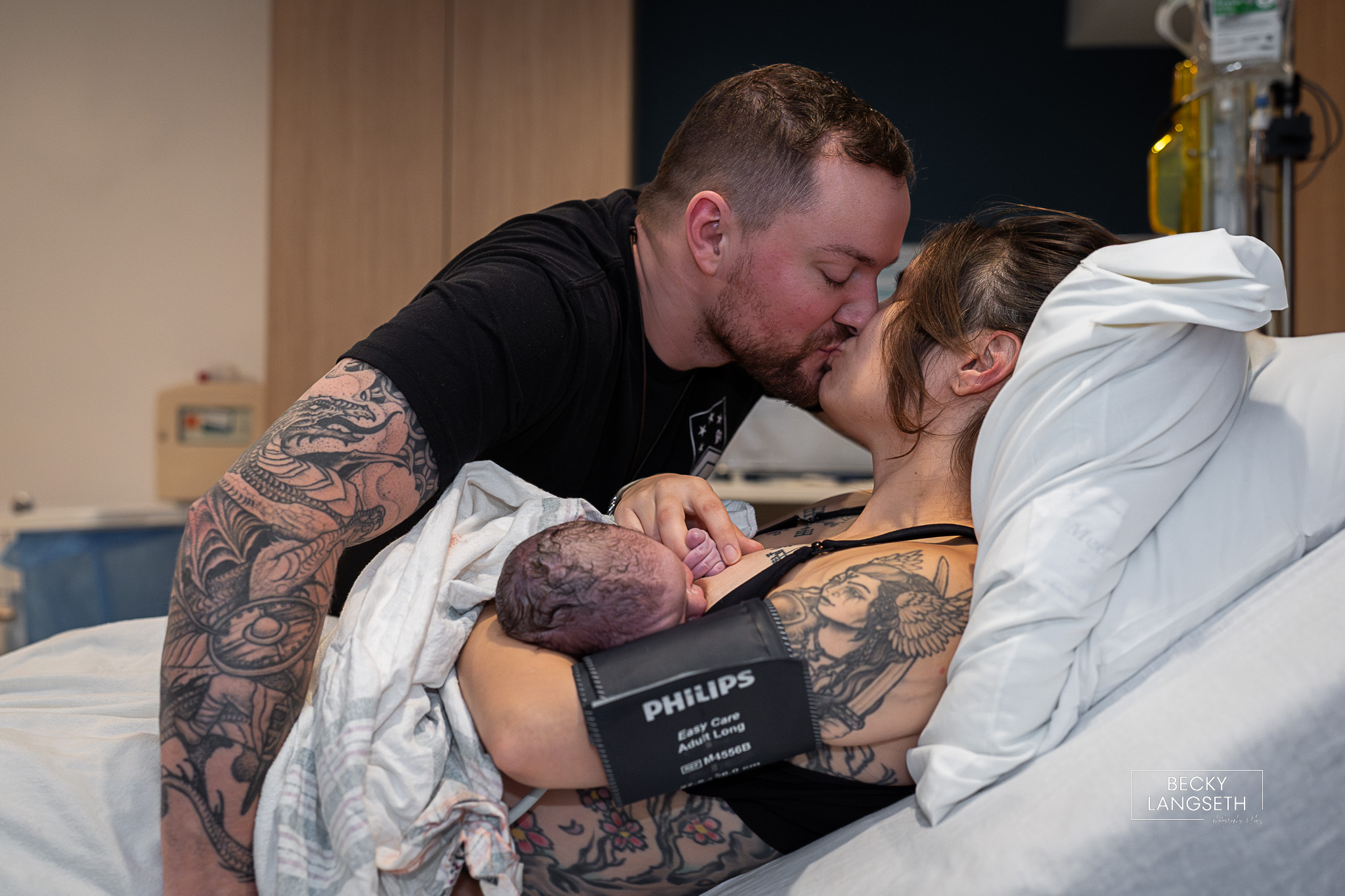 mom and dad kiss as they hold their newly born baby at Evergreen Hospital in Kirkland, Wa