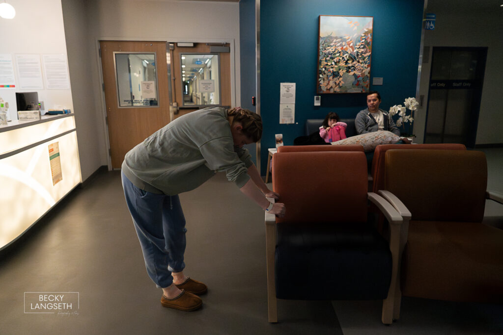 mother stands in the lobby of EvergreenHealth Family Maternity Center leaning against the chair as she goes through a contraction