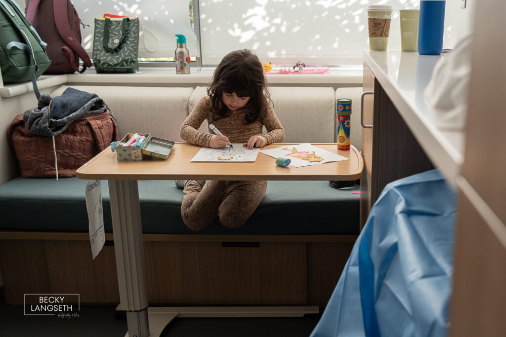 a child colors on a hospital tray table as she waits for her baby sister to be born