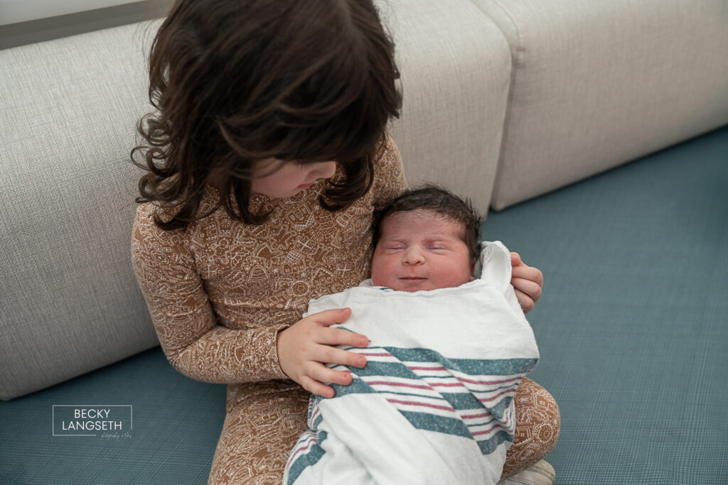big sister holding little sister for the first time at Evergreen Hospital in Kirkland