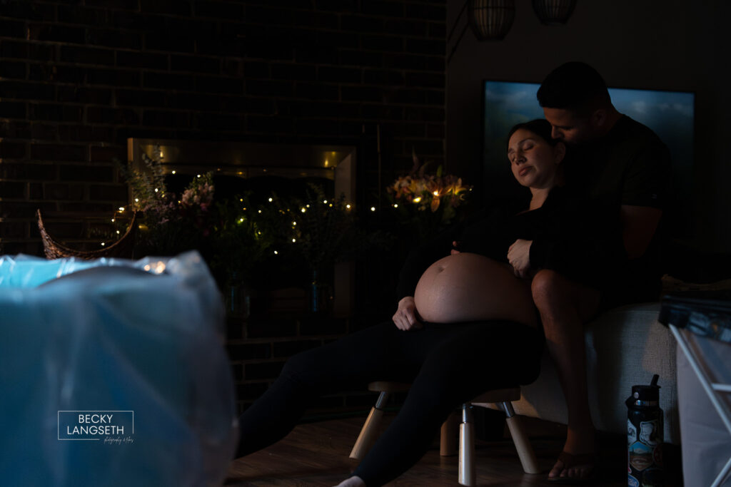 pregnant mother laboring with her husband supporting her behind