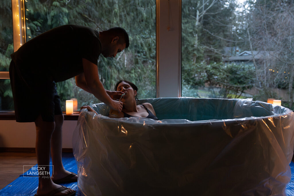 husband giving his wife a sip of water as she labors during her homebirth in Sammamish