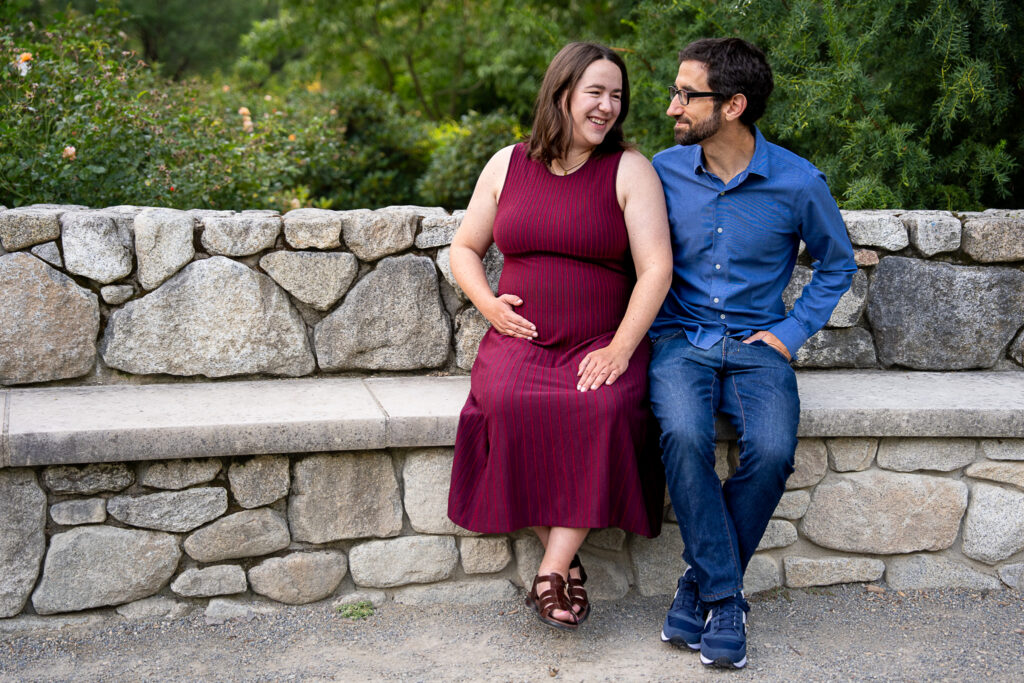 a couple sit together on a stone wall and laugh