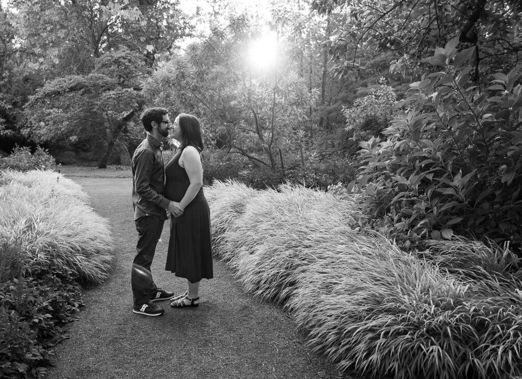 a backlit black/white image with a pregnant couple going noes to nose at the Arboretum in Seattle