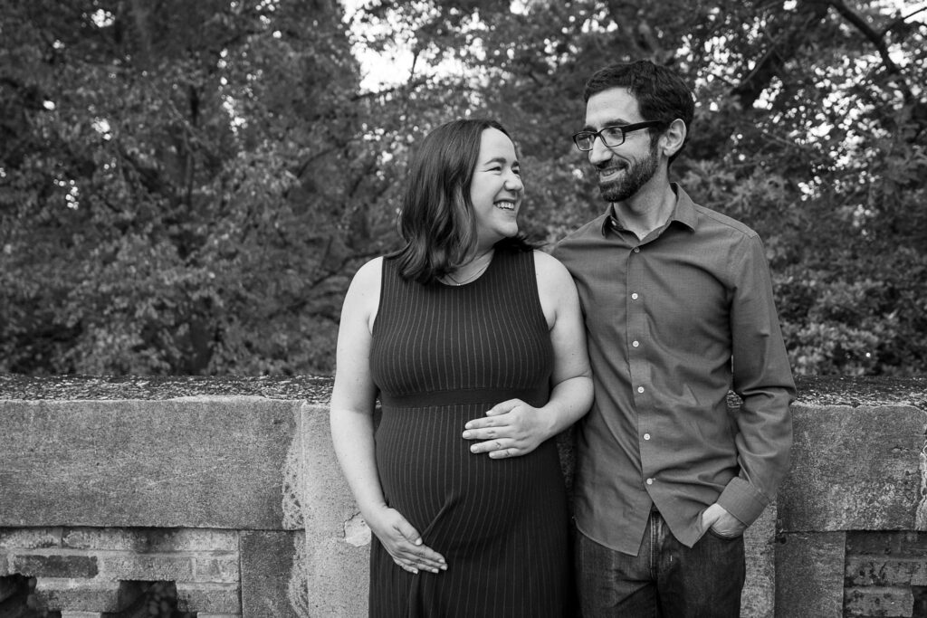 black and white images of a couple looking at each other and smiling as they lean against a stone fence
